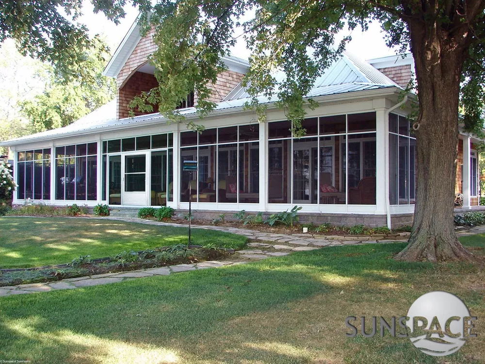 Large white glass sunroom on a home with a metal roof
